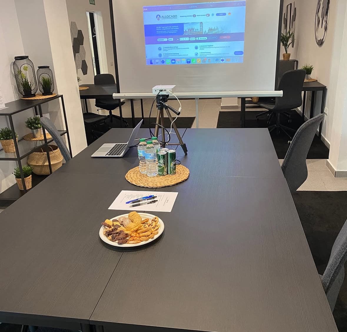 Workshop-Aufbau mit Projektion, Notizen und Snacks auf dem Tisch
