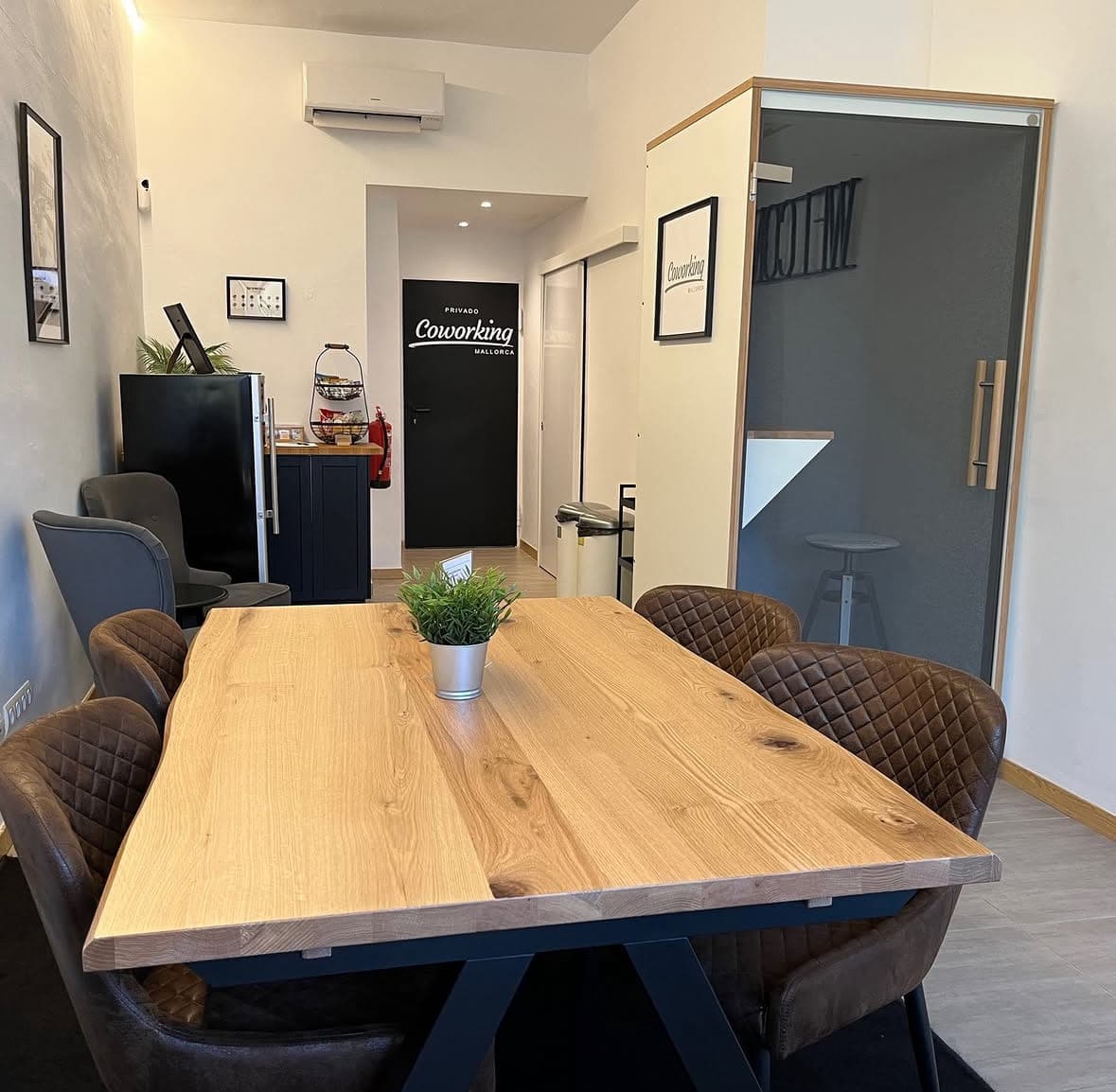 Gemeinsame Holztafel im Tagesgastbereich mit Kaffeebar im Hintergrund